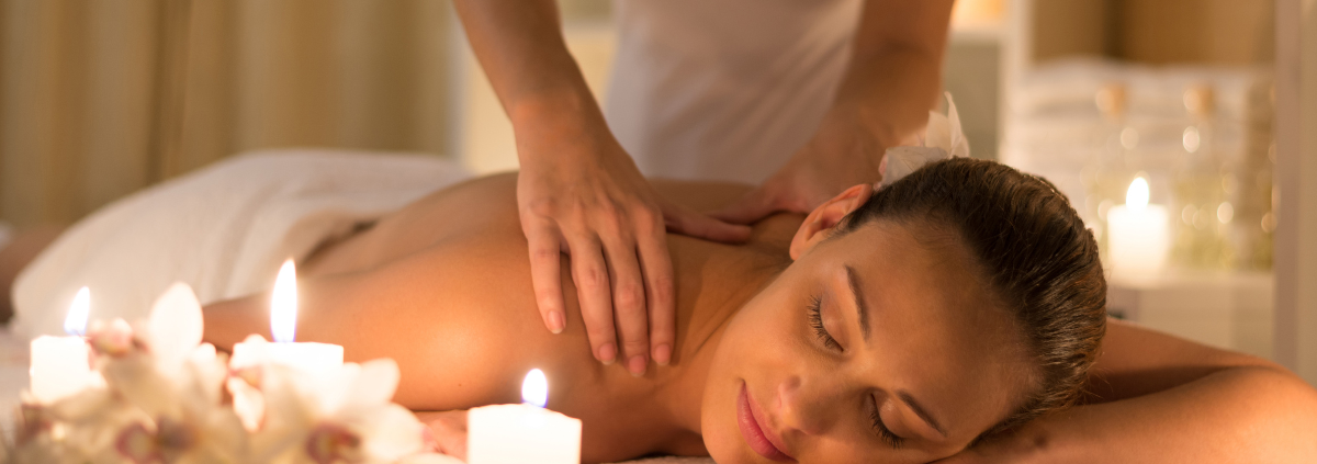 Woman receiving a relaxing massage surrounded by lit candles.