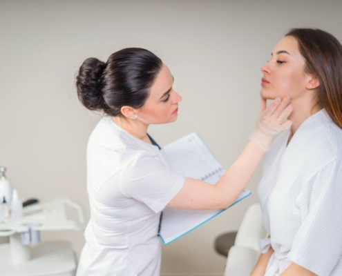 Dermatologist examining a female patient's skin closely during a consultation in a clinical setting.