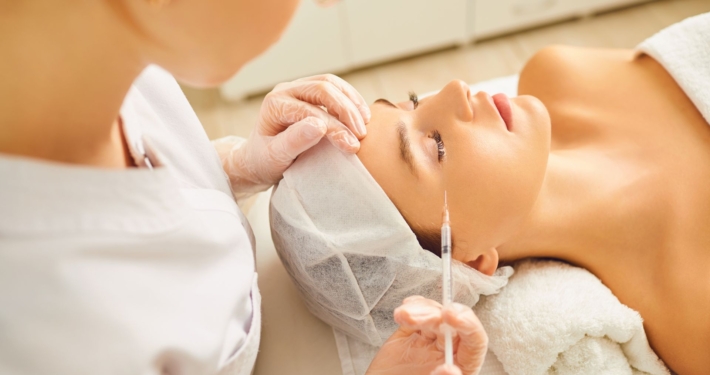 Medical professional injecting a client’s forehead during a facial rejuvenation procedure.
