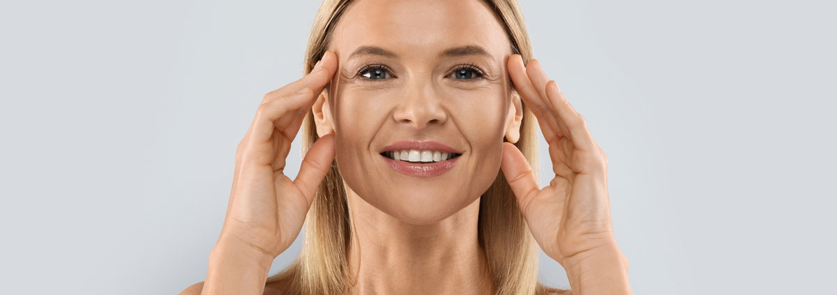 A beautiful woman holding her symmetrical face after receiving facial balancing treatments