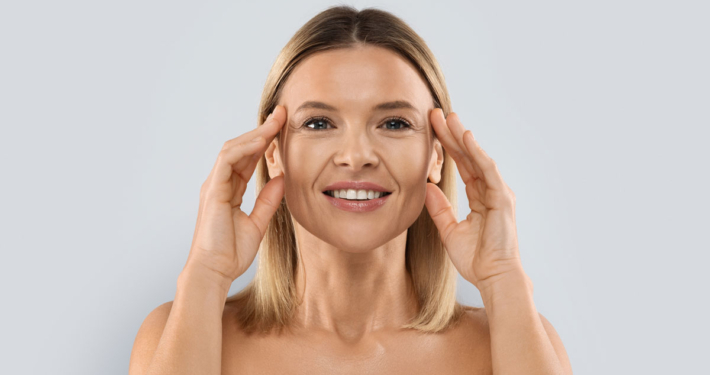 A beautiful woman holding her symmetrical face after receiving facial balancing treatments